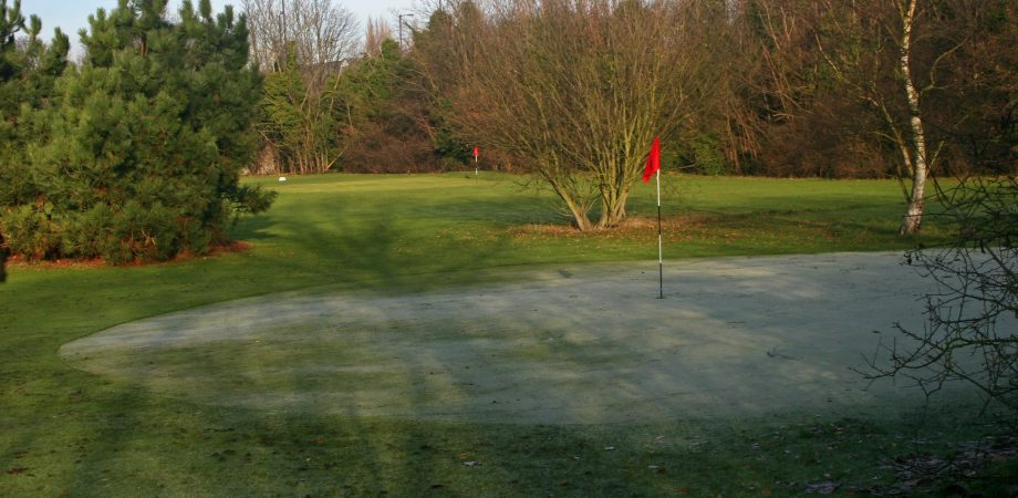 golf greens with red flag and dusting of snow