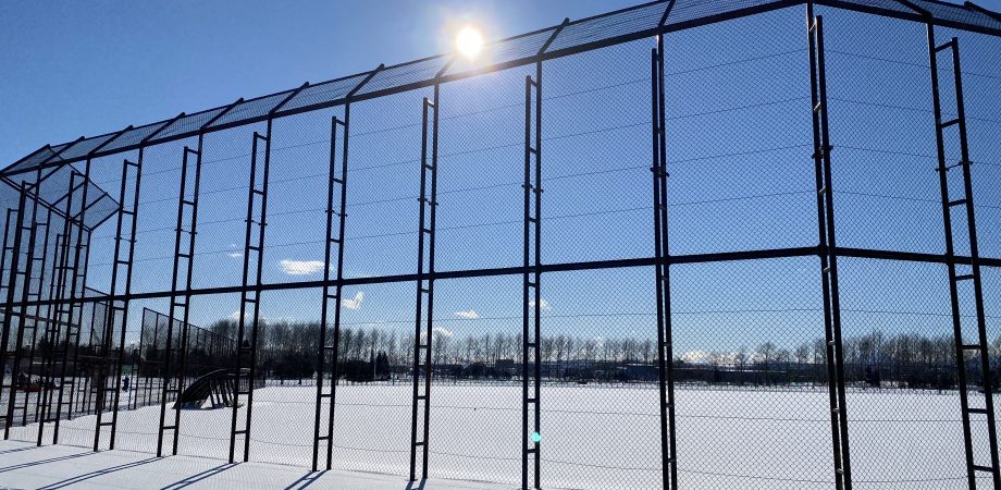 baseball field covered in snow with a blue sky and sun shining