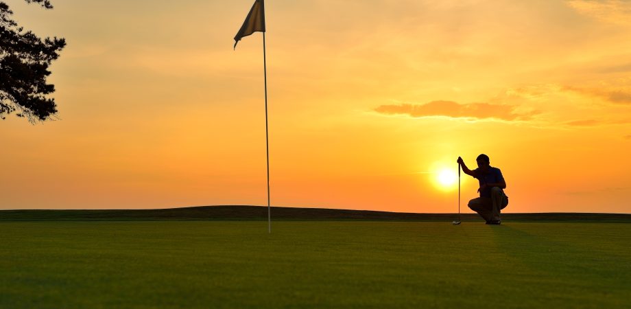 silhouette of a young man playing golf at sunset