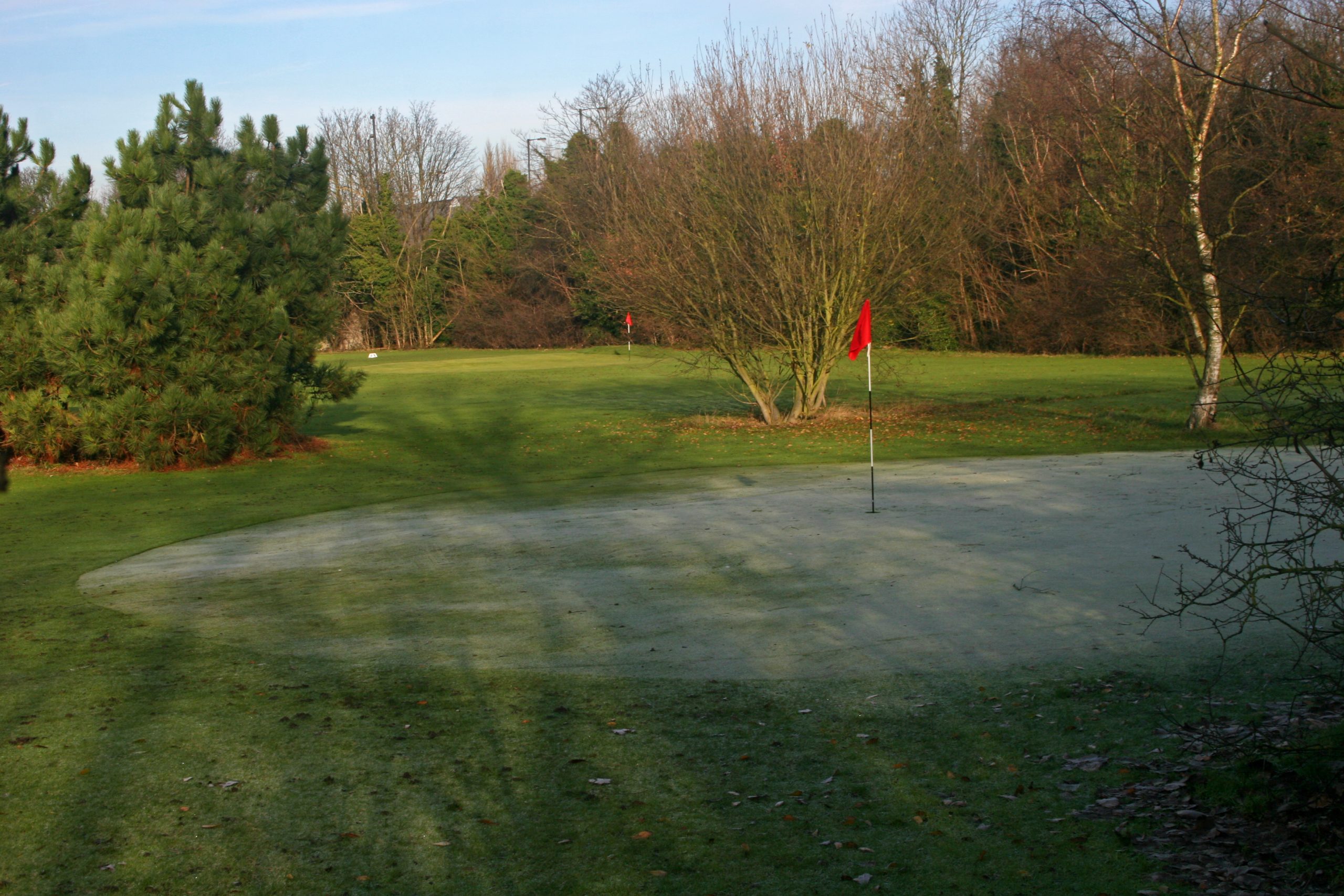 golf greens with red flag and dusting of snow