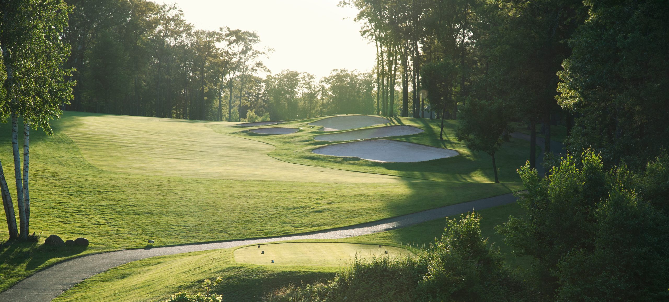 Back lit golf fairway with sand traps viewed from the tee box