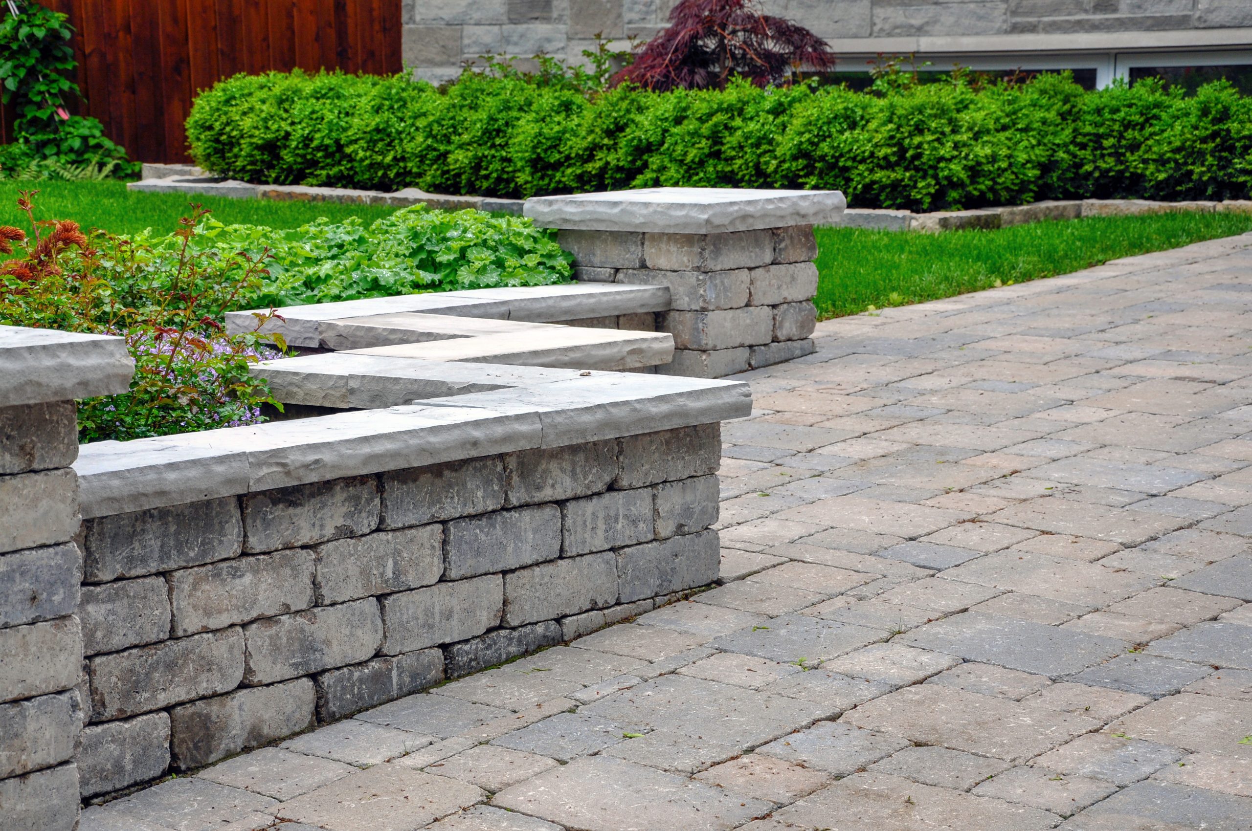 A seat wall with pillars and natural stone coping helps define a