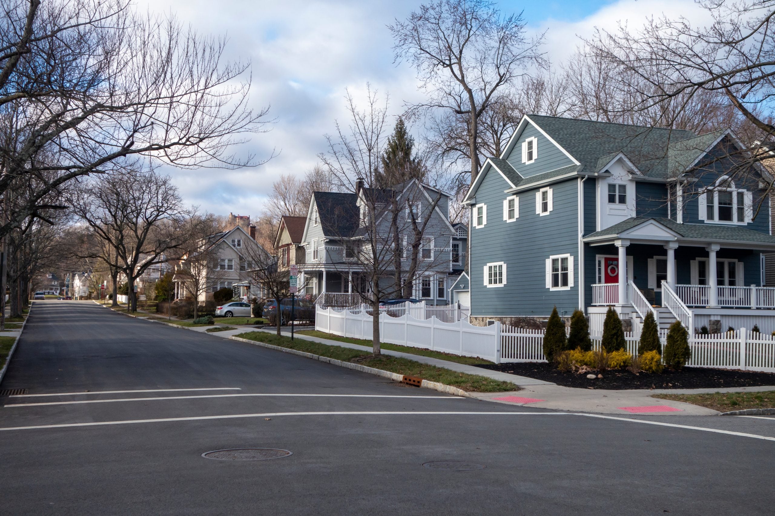 street and sidewalk of suburban homes with leafless trees late fall-winter season