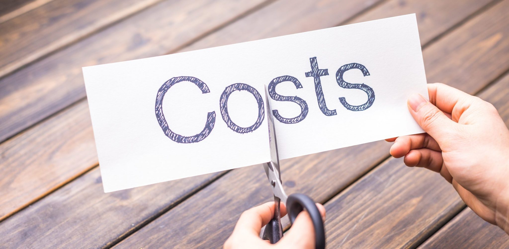 costs written on paper and someone cutting the paper in half