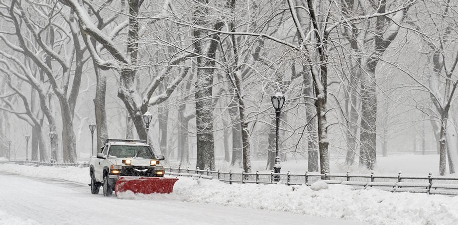 Truck with snowplow clearing road during snowstorm