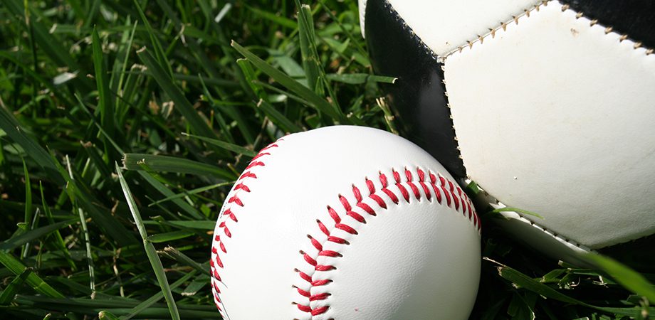 baseball and soccer ball sitting on a field